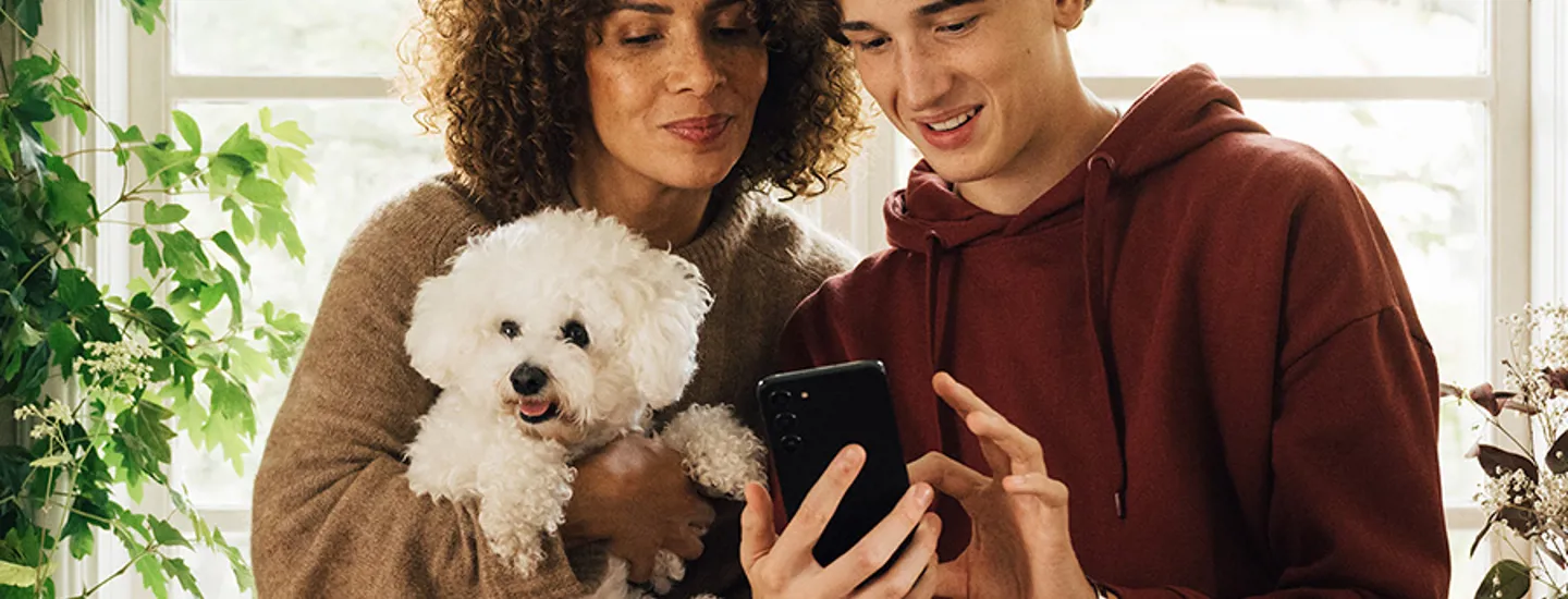Kvinna, man och hund som kikar på en mobil
