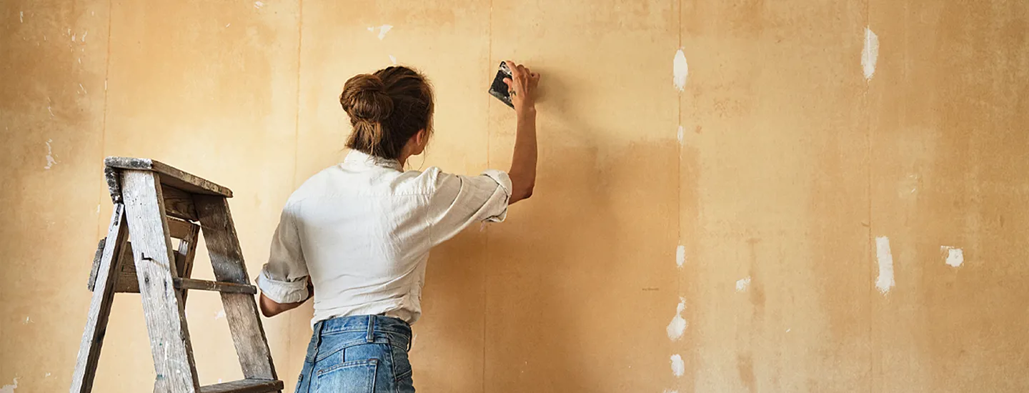 Kvinna renoverar gul vägg inomhus