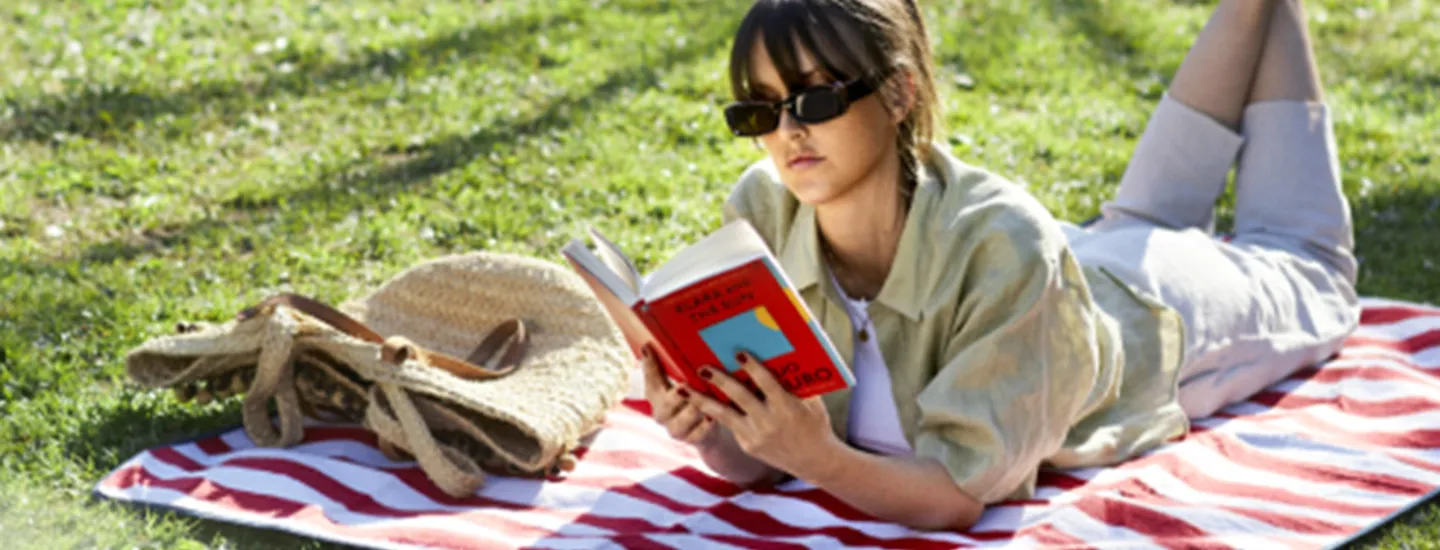 En tjej som ligger på en filt och läser bok