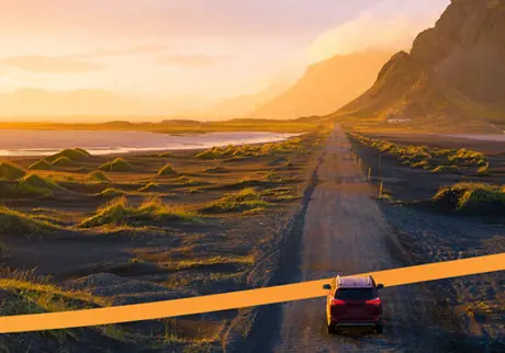 Bil på landsväg i vackert landskap i solnedgång